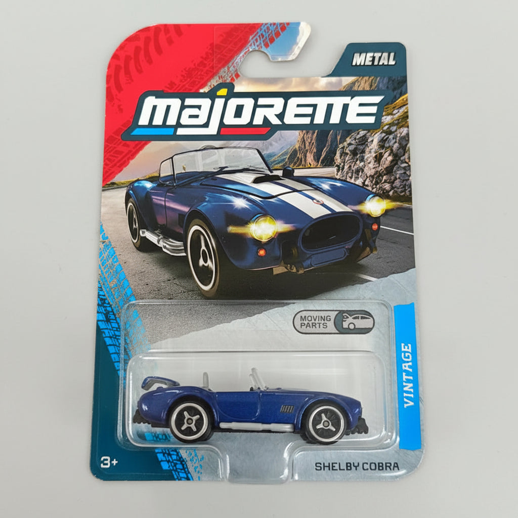 Blue Shelby Cobra toy car in packaging with Majorette branding on a textured surface.